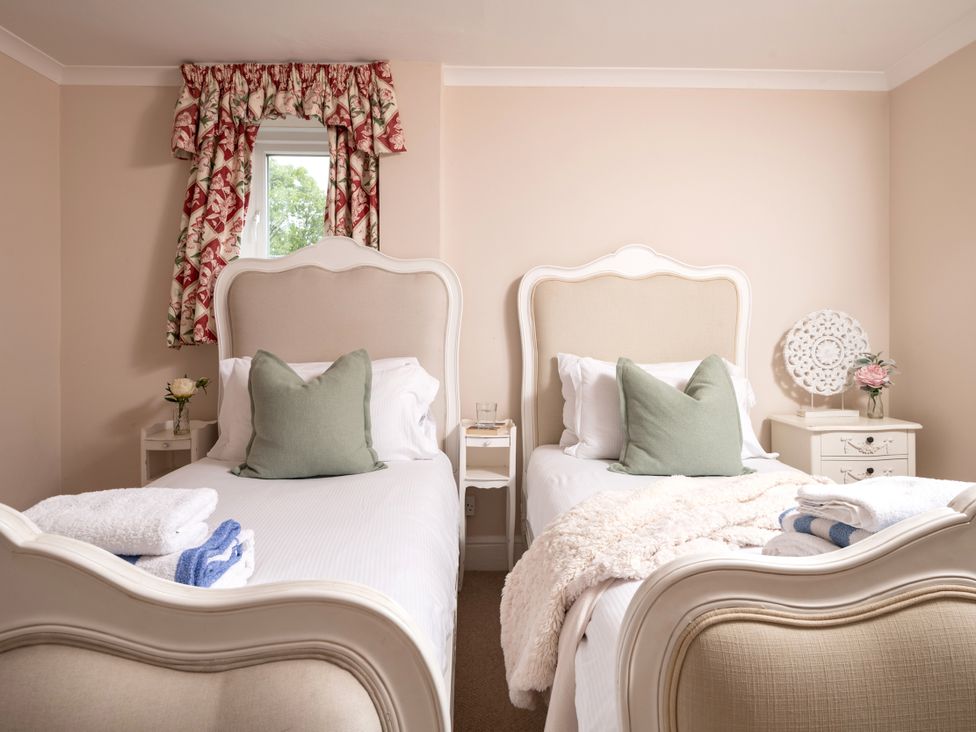 A bedroom with two beds and floral curtains at The Downwood in Blandford Forum