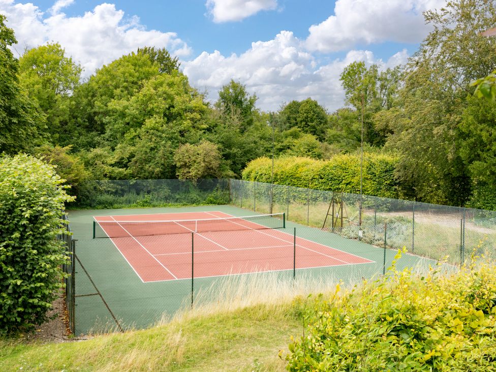 A tennis court surrounded by trees at The Downwood in Blandford Forum