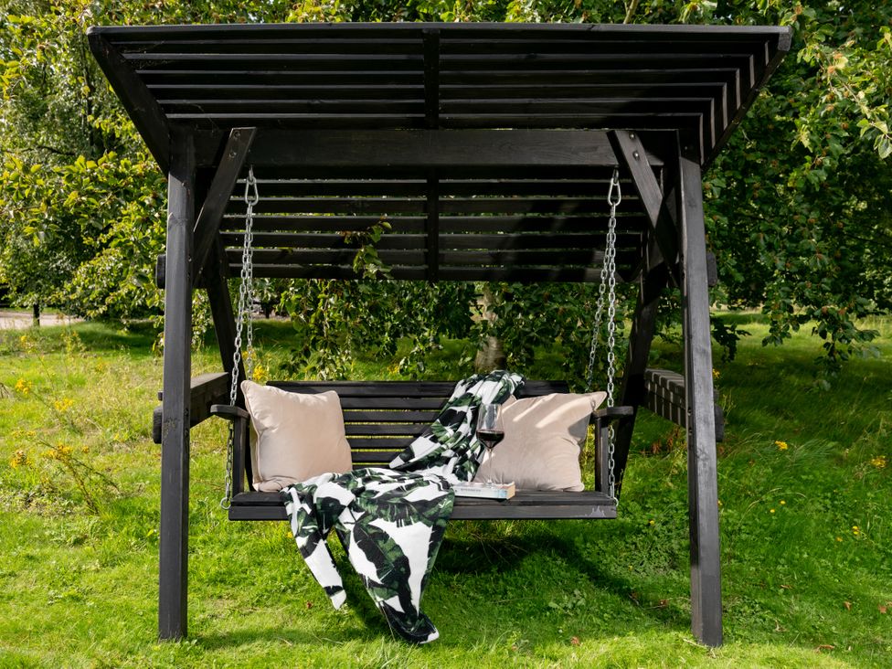 A swing with pillows and a blanket in a park at The Downwood in Blandford Forum