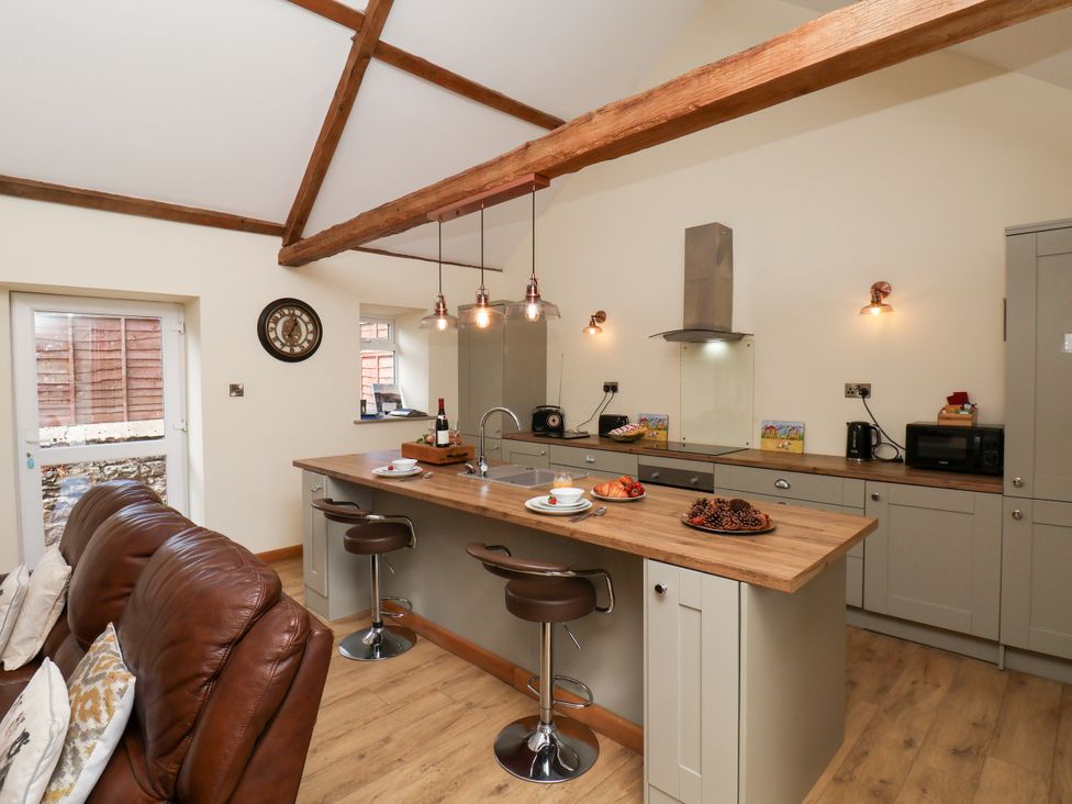 A kitchen with an island and bar stools at Crabtree Cottage in Suffield near Scalby