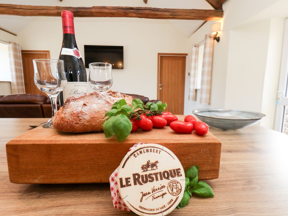 A kitchen with a cutting board, wine, cheese, and vegetables at Crabtree Cottage, Suffield near Scalby