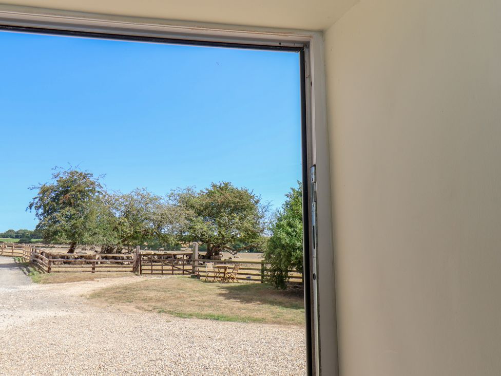 A view of a fence and trees from a doorway at Crabtree Cottage Suffield near Scalby