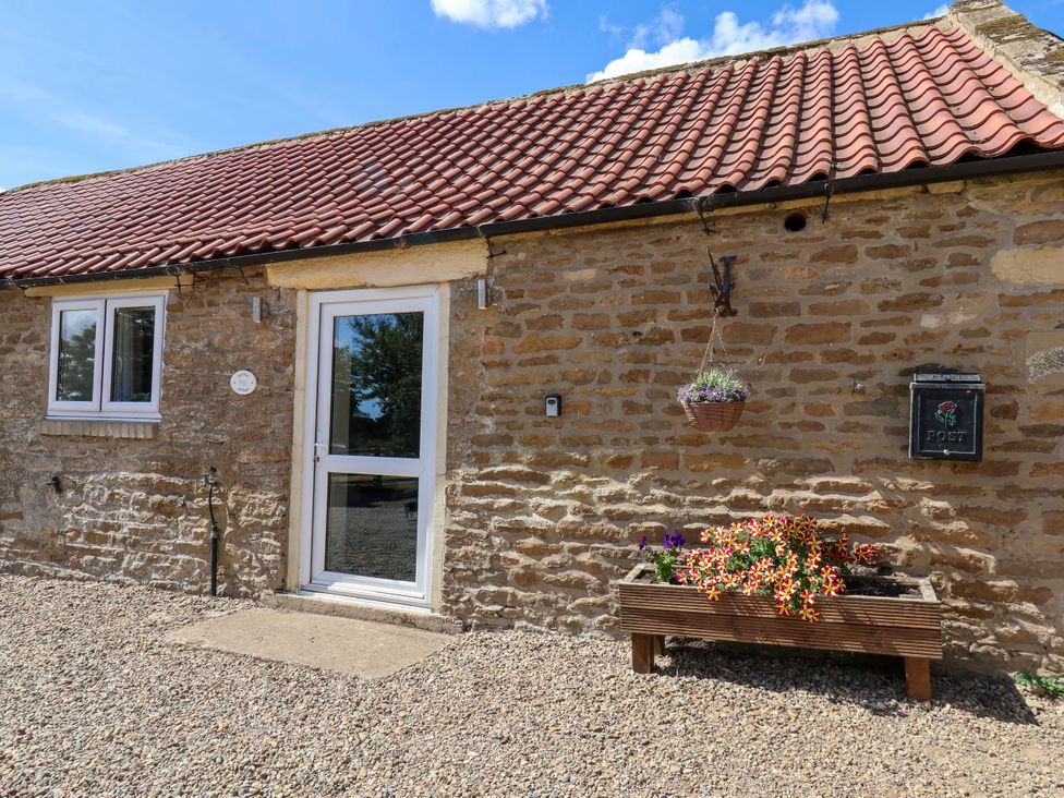 An entrance to a cottage with a door, window, and flower box at Crabtree Cottage Suffield near Scalby