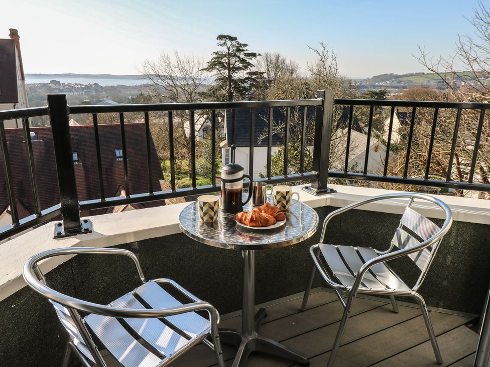 A balcony with a table, chairs, coffee maker, and croissants at Cambrie in Tenby