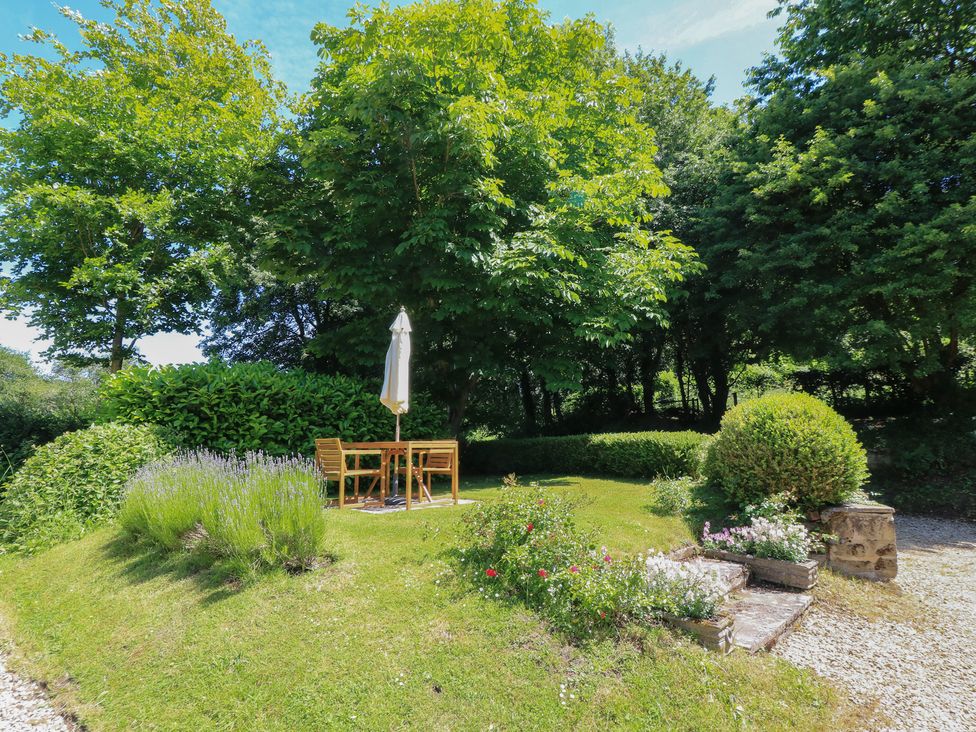 A garden with a table and chairs under an umbrella at The Barn at Frog Pond Farm Antsy near Tisbury