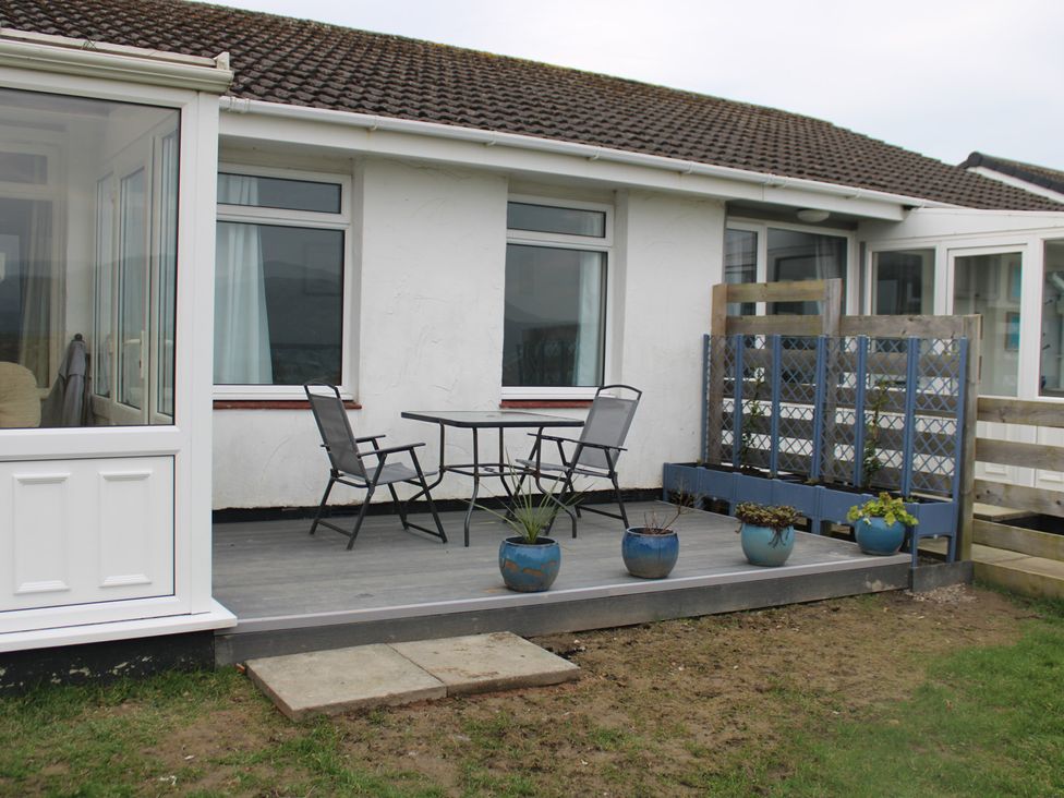 A patio with a table and chairs at Hafod-y-Gors in Fairbourne