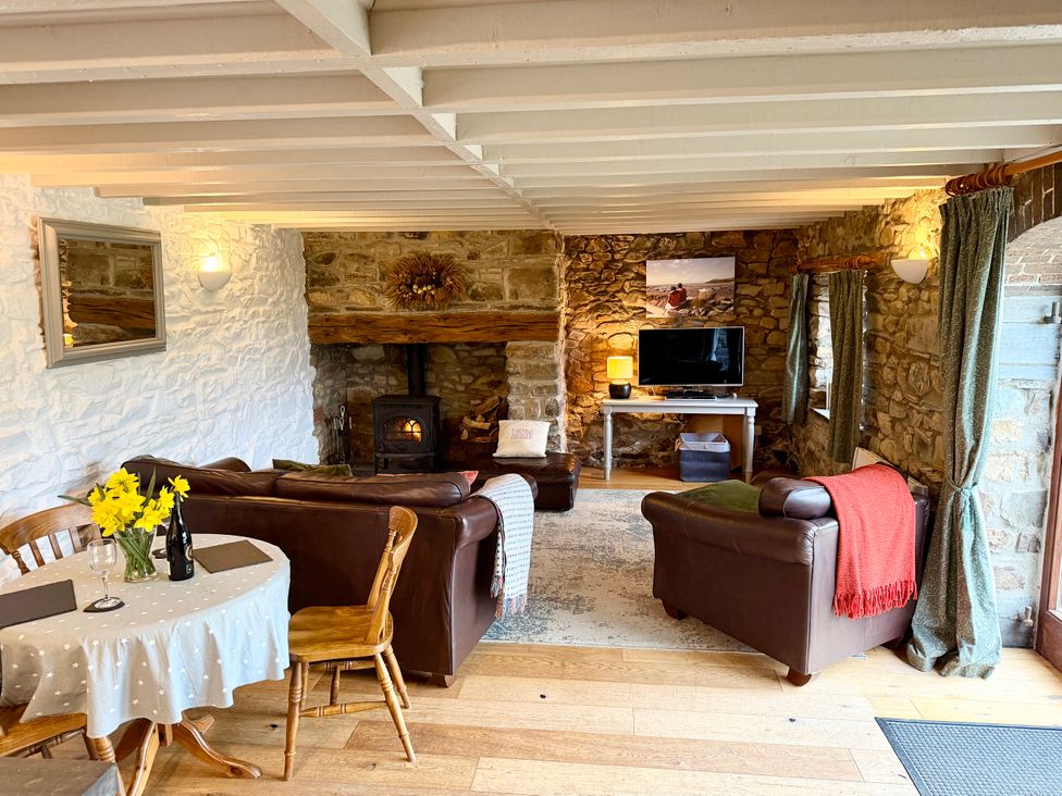 A living room with a sofa, dining table, and television at Stable Cottage in Newport, Pembrokeshire