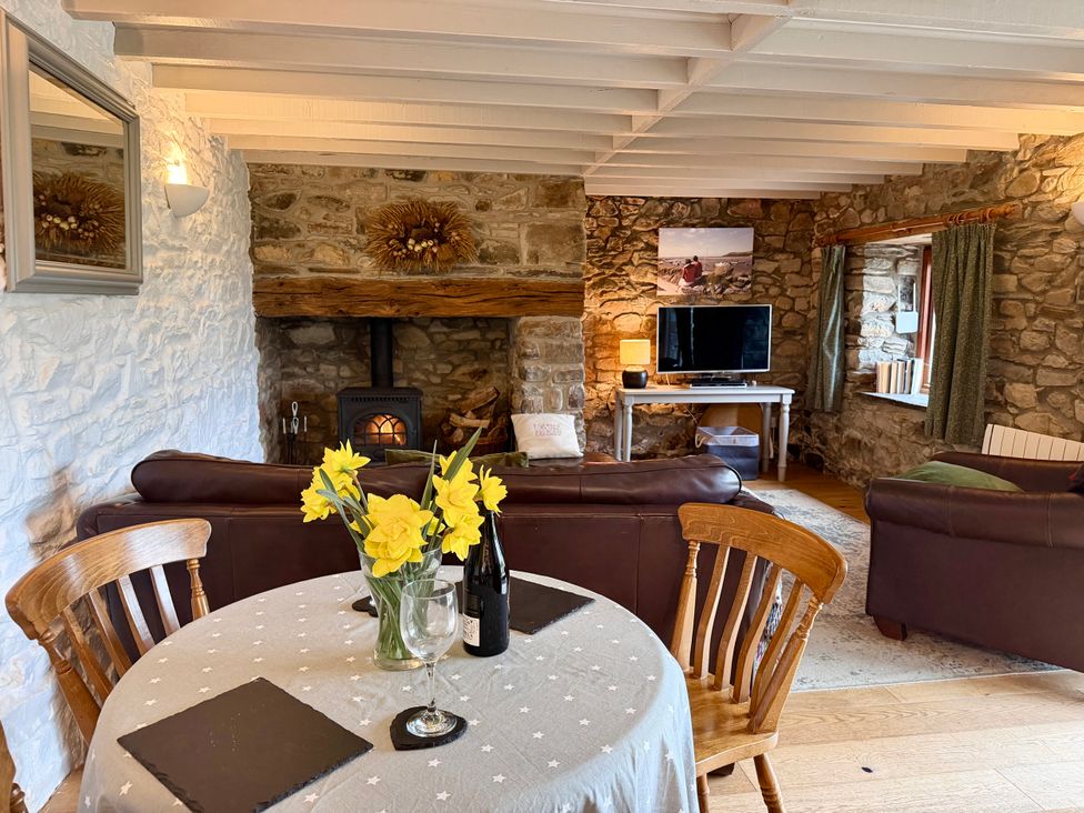 A living room with a sofa, a table, and a television at Stable Cottage in Newport, Pembrokeshire
