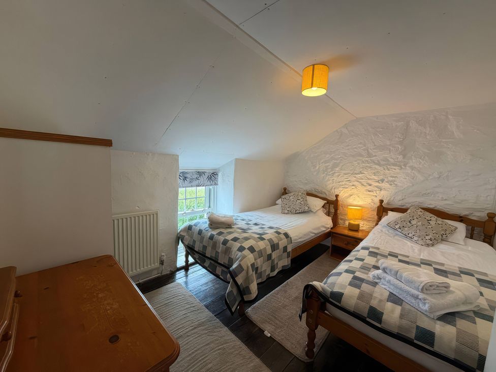 A bedroom with two single beds and a window at Derlwyn in Newport, Pembrokeshire