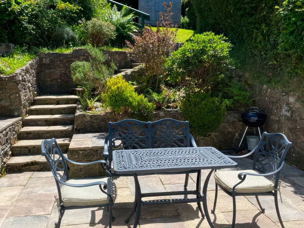 A garden with a table and chairs and steps at Derlwyn Newport, Pembrokeshire