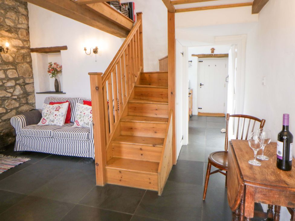 A living room with a couch and a staircase at West End Cottage in Newport, Pembrokeshire