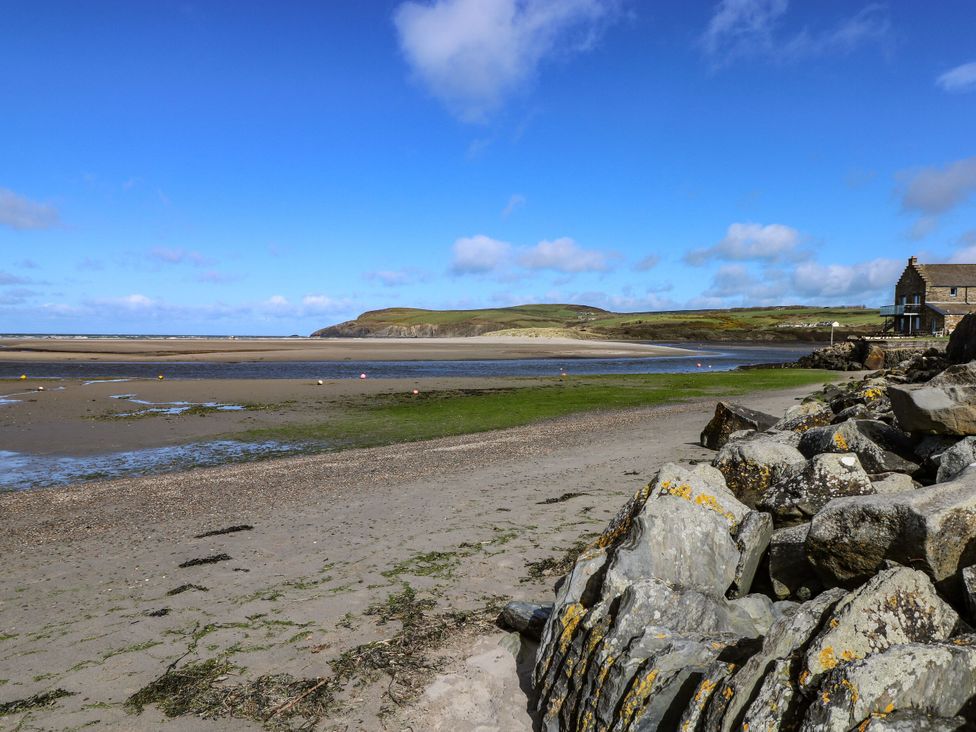Sandy beach with rocks and house at West End Cottage in Newport, Pembrokeshire
