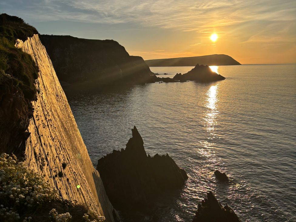 A view of cliffs and ocean with the sun setting at West End Cottage in Newport, Pembrokeshire