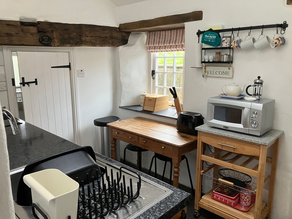 A kitchen with a table and various appliances at West End Cottage in Newport, Pembrokeshire