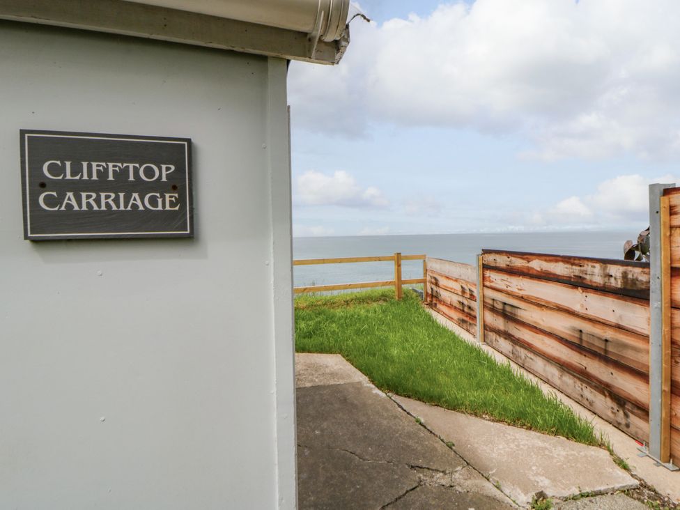 A sign reading Clifftop Carriage next to a view of the ocean in Aberporth, Ceredigion