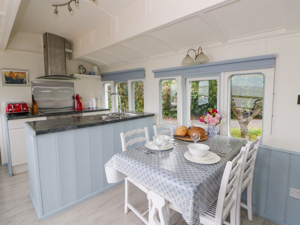 A kitchen with a table set for dining at Clifftop Carriage in Aberporth, Ceredigion