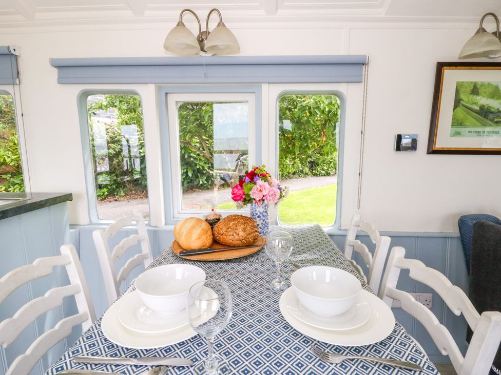 A dining room with a table set with bowls and a flower vase at Clifftop Carriage Aberporth, Ceredigion