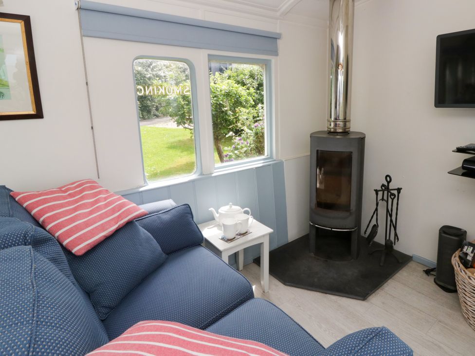 A living room with a sofa and a wood stove at Clifftop Carriage, Aberporth, Ceredigion