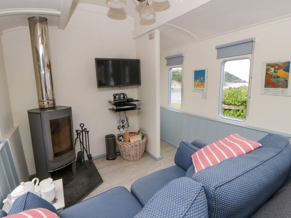 A living room with a stove and television at Clifftop Carriage in Aberporth, Ceredigion