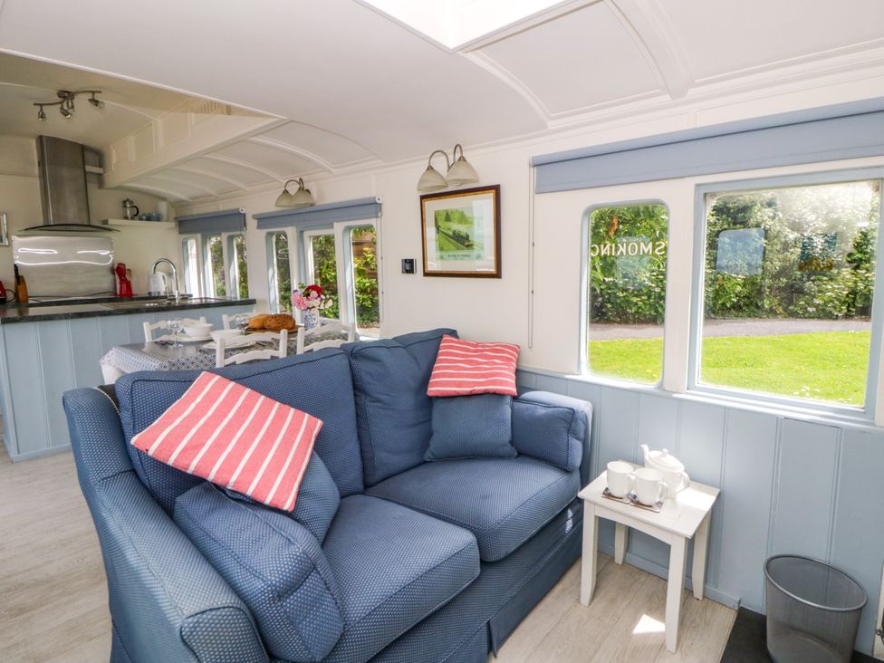 A living room with a sofa and kitchen counter at Clifftop Carriage in Aberporth, Ceredigion