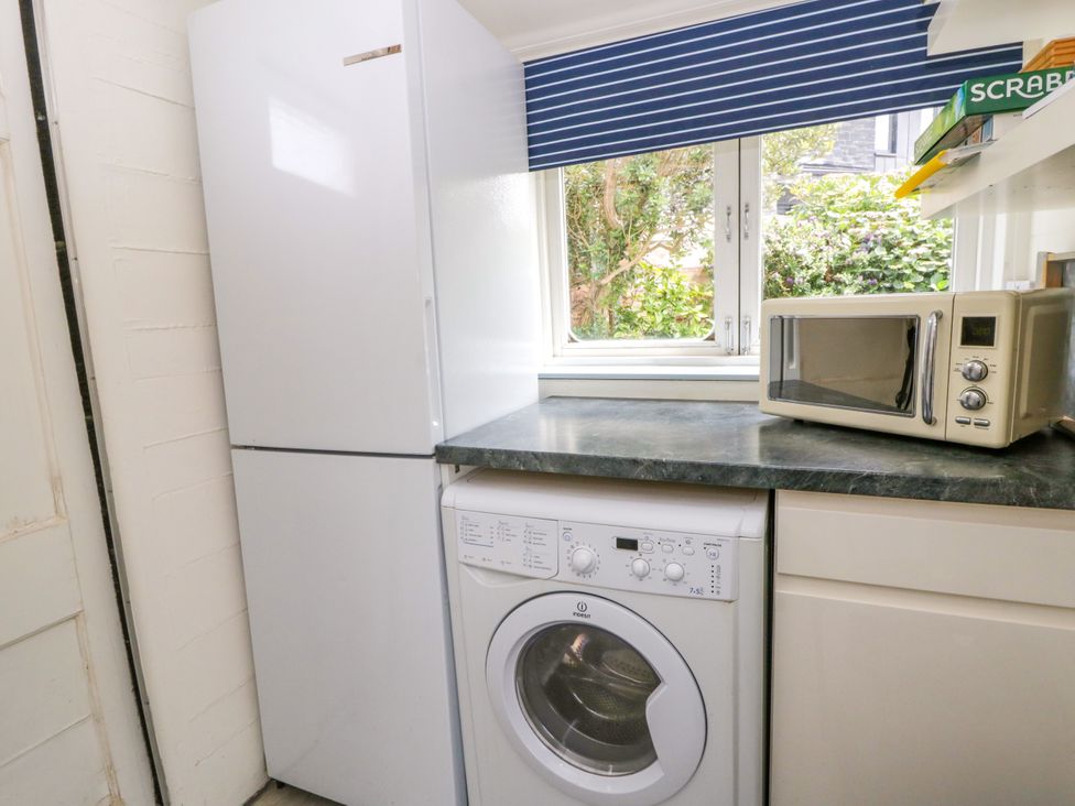 A laundry room with a fridge and washing machine at Clifftop Carriage Aberporth, Ceredigion
