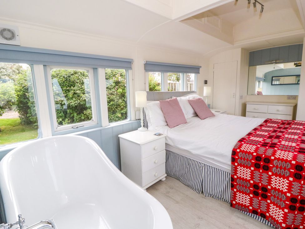 A bedroom with a bed and bathtub at Clifftop Carriage in Aberporth, Ceredigion