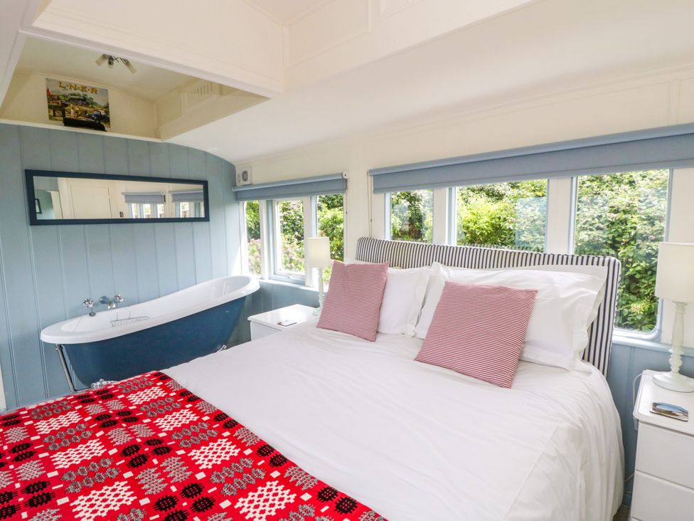A bedroom with a bed and a bathtub at Clifftop Carriage Aberporth, Ceredigion