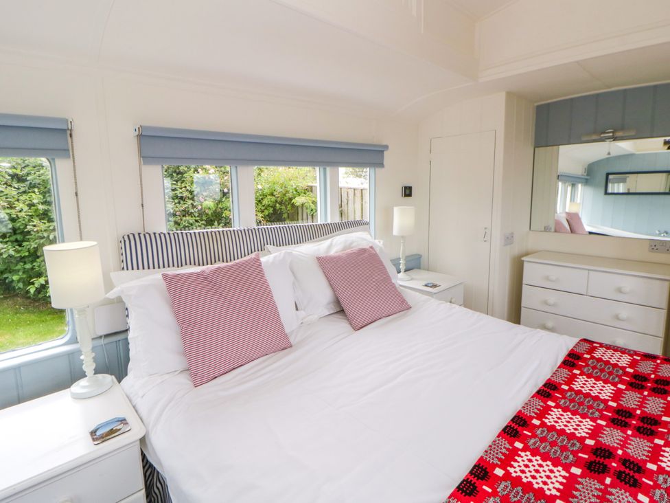 A bedroom with a bed and furniture at Clifftop Carriage in Aberporth, Ceredigion
