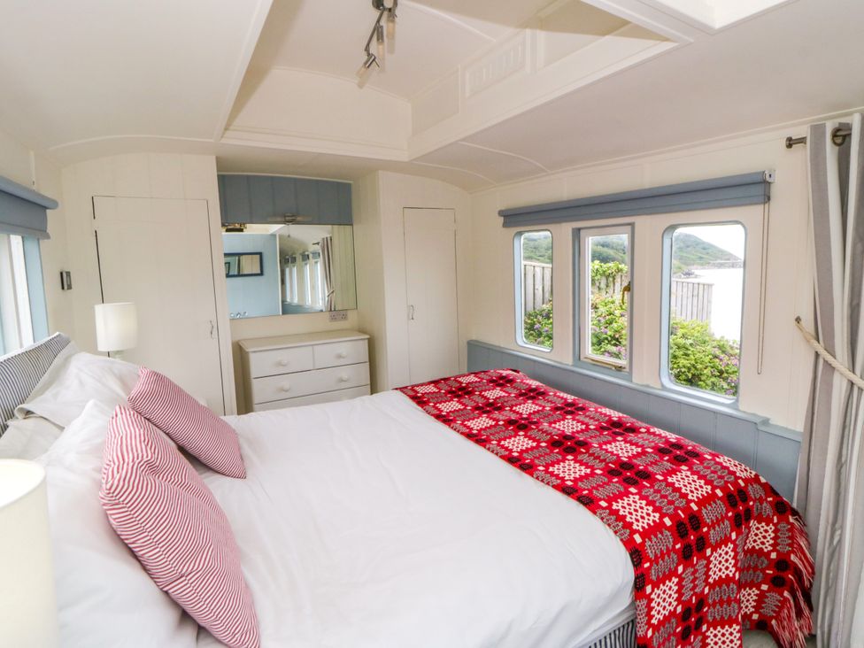 A bedroom with a bed and dresser at Clifftop Carriage in Aberporth, Ceredigion