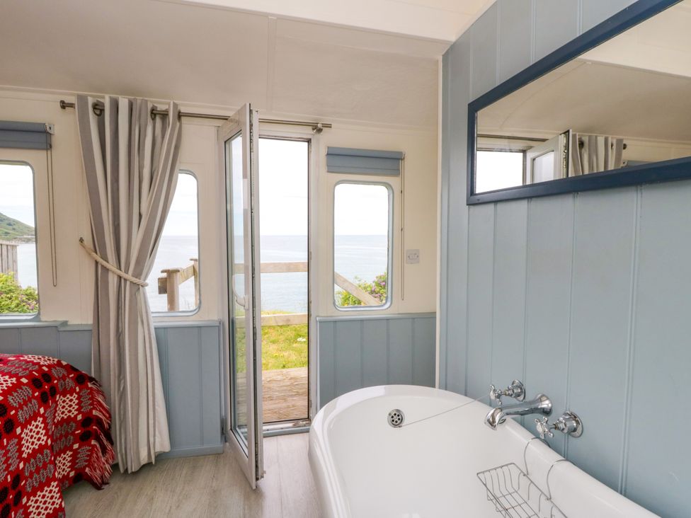 A bathroom with a bathtub and window at Clifftop Carriage in Aberporth, Ceredigion