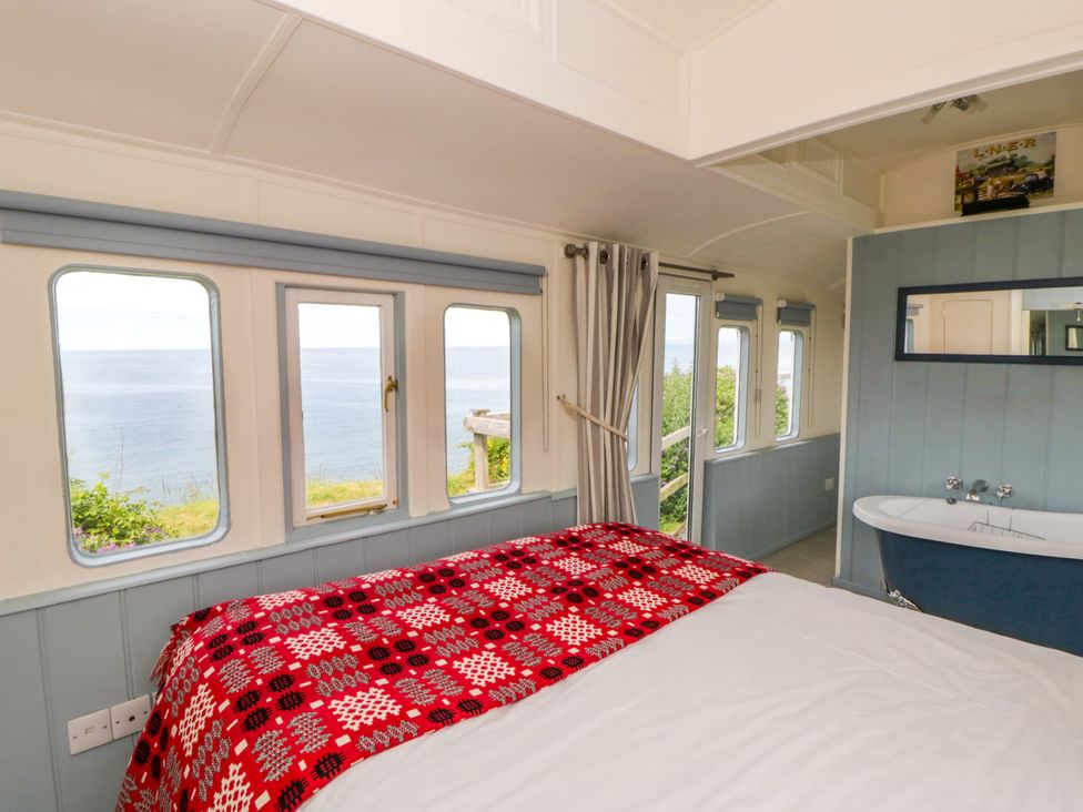 A bedroom with a bed and bathtub at Clifftop Carriage, Aberporth, Ceredigion