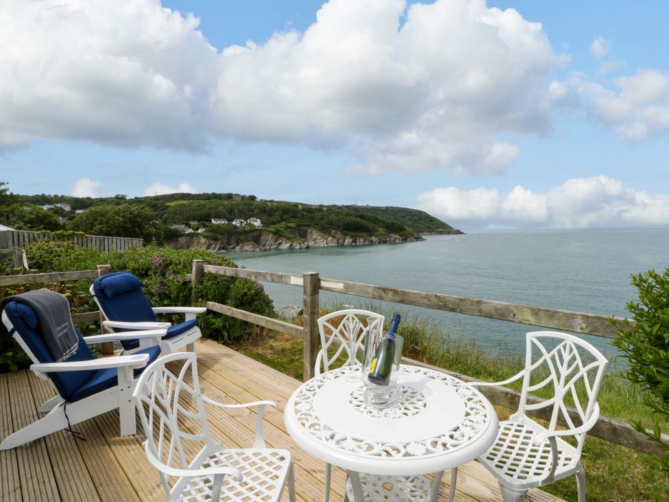 A patio area with chairs and table overlooking the ocean at Clifftop Carriage in Aberporth, Ceredigion