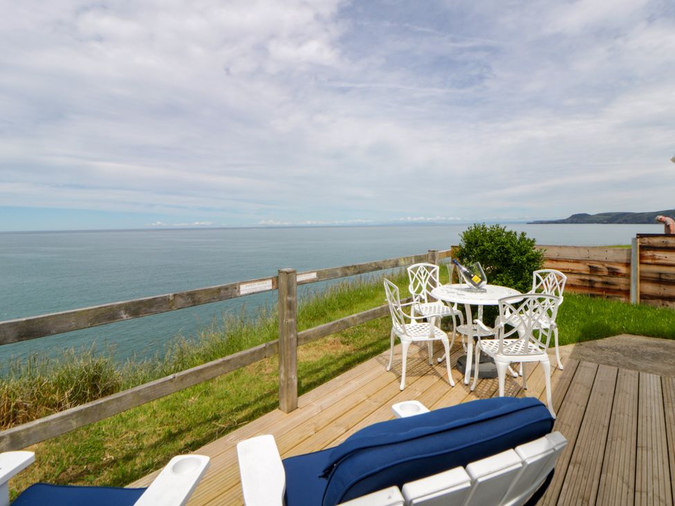 An outdoor area with a table and chairs overlooking the ocean at Clifftop Carriage Aberporth, Ceredigion