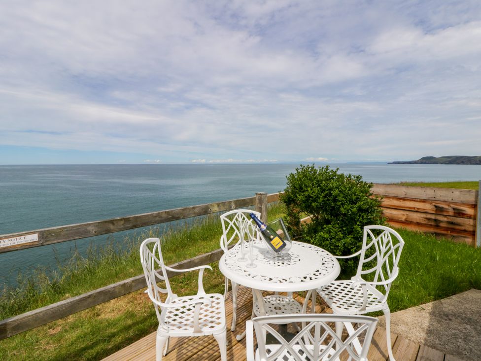 An outdoor seating area with a table and chairs at Clifftop Carriage in Aberporth, Ceredigion