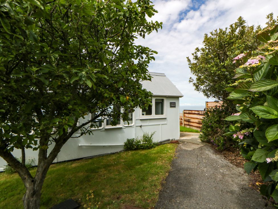 A pathway leading to a house with trees and bushes at Clifftop Carriage Aberporth, Ceredigion