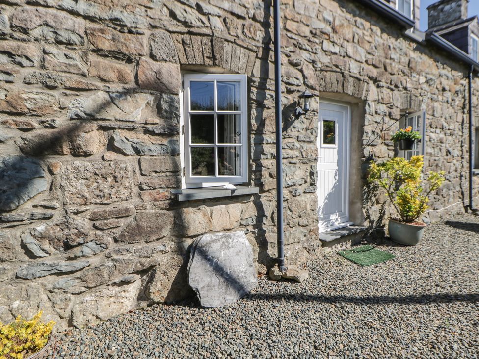 A stone wall with a window and door at End Cottage in Newport, Pembrokeshire