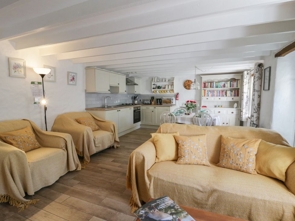 A living room with a sofa and kitchen area at End Cottage in Newport, Pembrokeshire