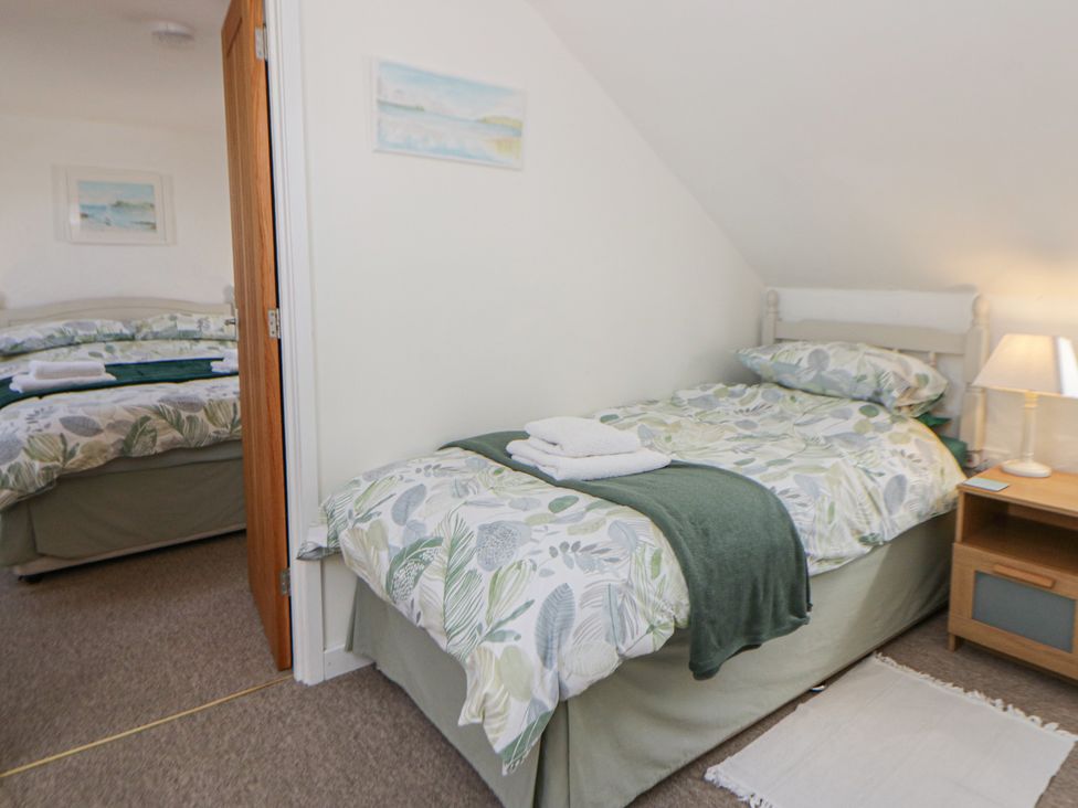 A bedroom with two beds and a bedside table at End Cottage Newport, Pembrokeshire