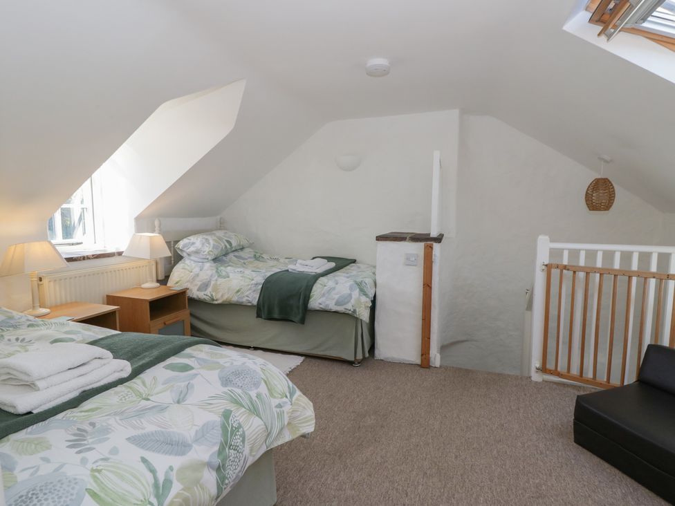 A bedroom with two beds and a nightstand at End Cottage in Newport, Pembrokeshire