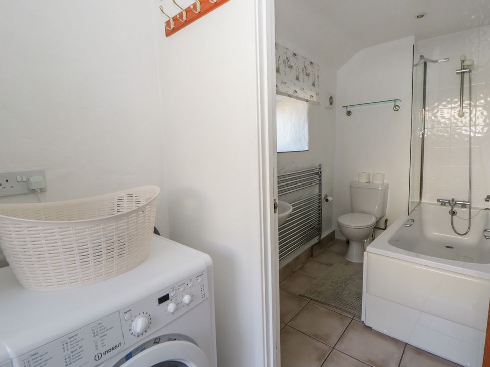 A bathroom with a washing machine and bath at End Cottage in Newport, Pembrokeshire