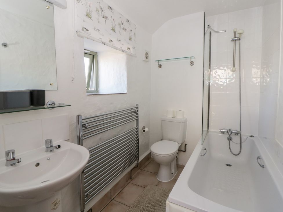 A bathroom with a bathtub, sink, toilet, and towel radiator at End Cottage Newport, Pembrokeshire