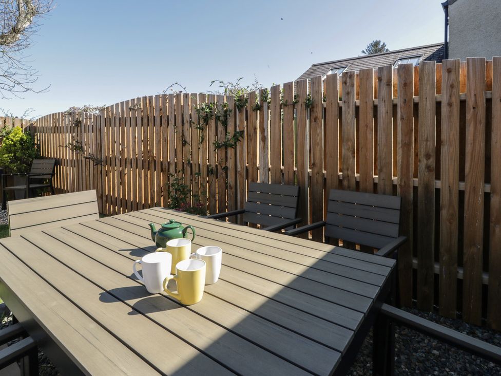 A garden with a table and chairs and mugs at End Cottage, Newport, Pembrokeshire