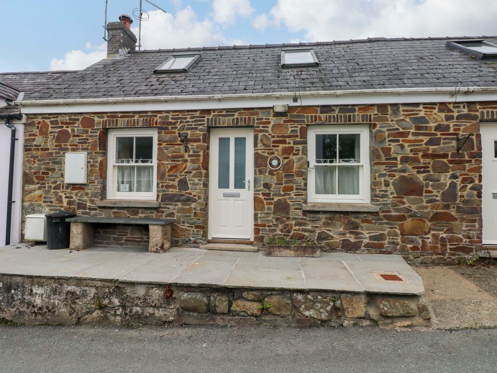A stone cottage with a front door and windows at Brynawelon, Newport, Pembrokeshire