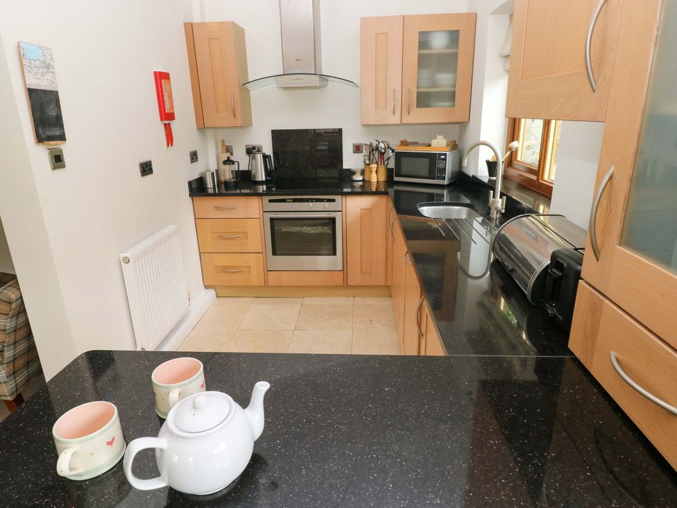 A kitchen with wooden cabinets and appliances at Brynawelon Newport, Pembrokeshire