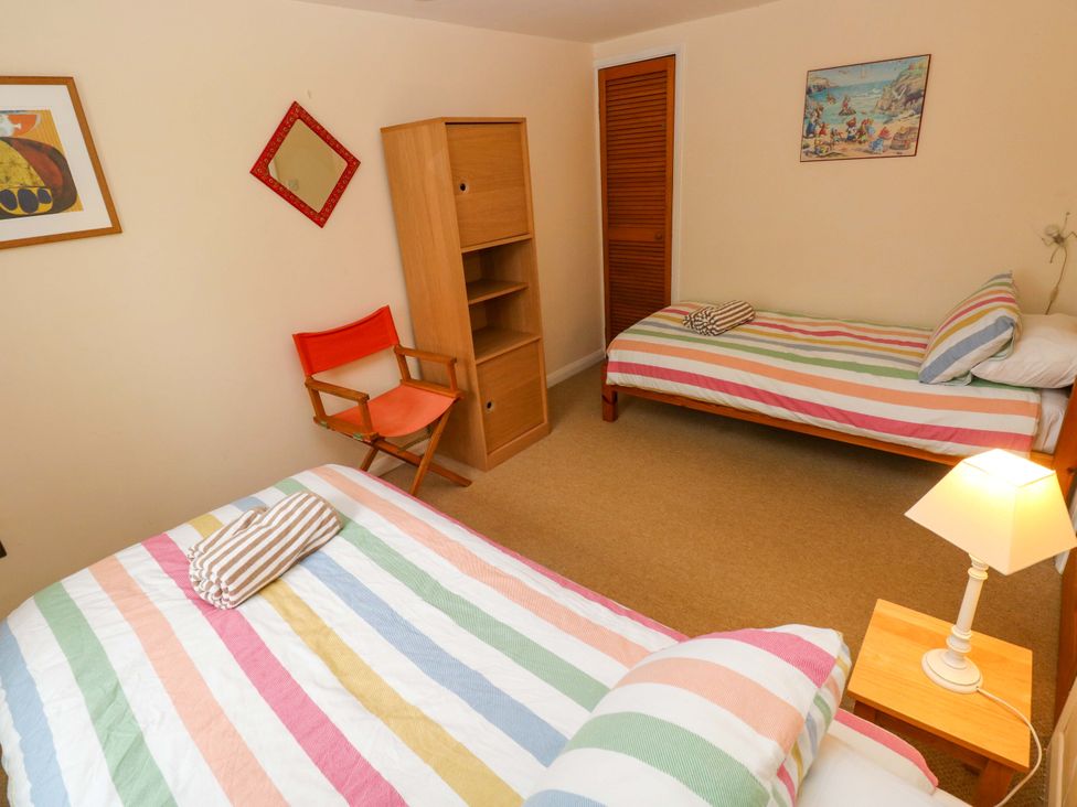 A bedroom with two beds and a bookshelf at Brynawelon, Newport, Pembrokeshire