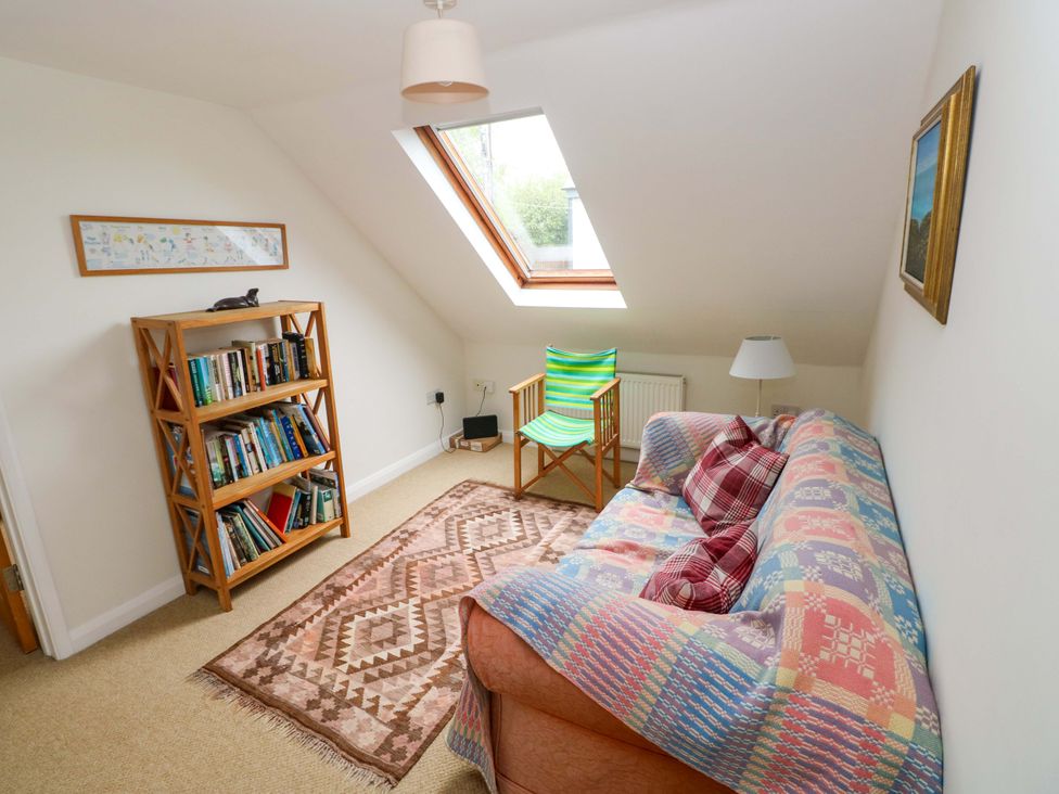 A snug with a bookshelf and chair at Brynawelon in Newport, Pembrokeshire