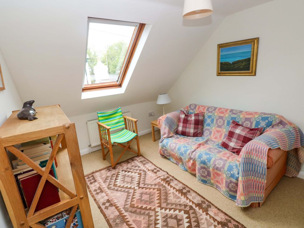 A snug with a sofa, armchair and bookcase at Brynawelon, Newport, Pembrokeshire