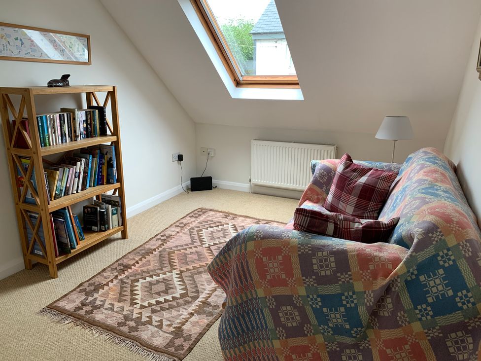 A snug with a bookshelf and sofa at Brynawelon in Newport, Pembrokeshire