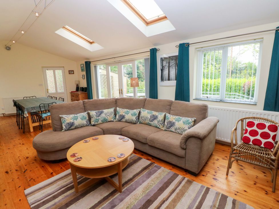 A living room with a sofa and a dining table at Greenbanks, Dinas Cross, Pembrokeshire