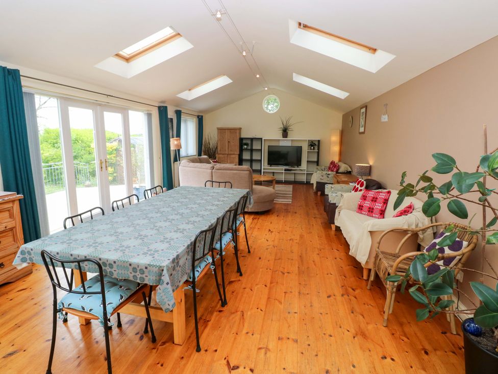 A living room with a dining table and a sofa at Greenbanks in Dinas Cross, Pembrokeshire